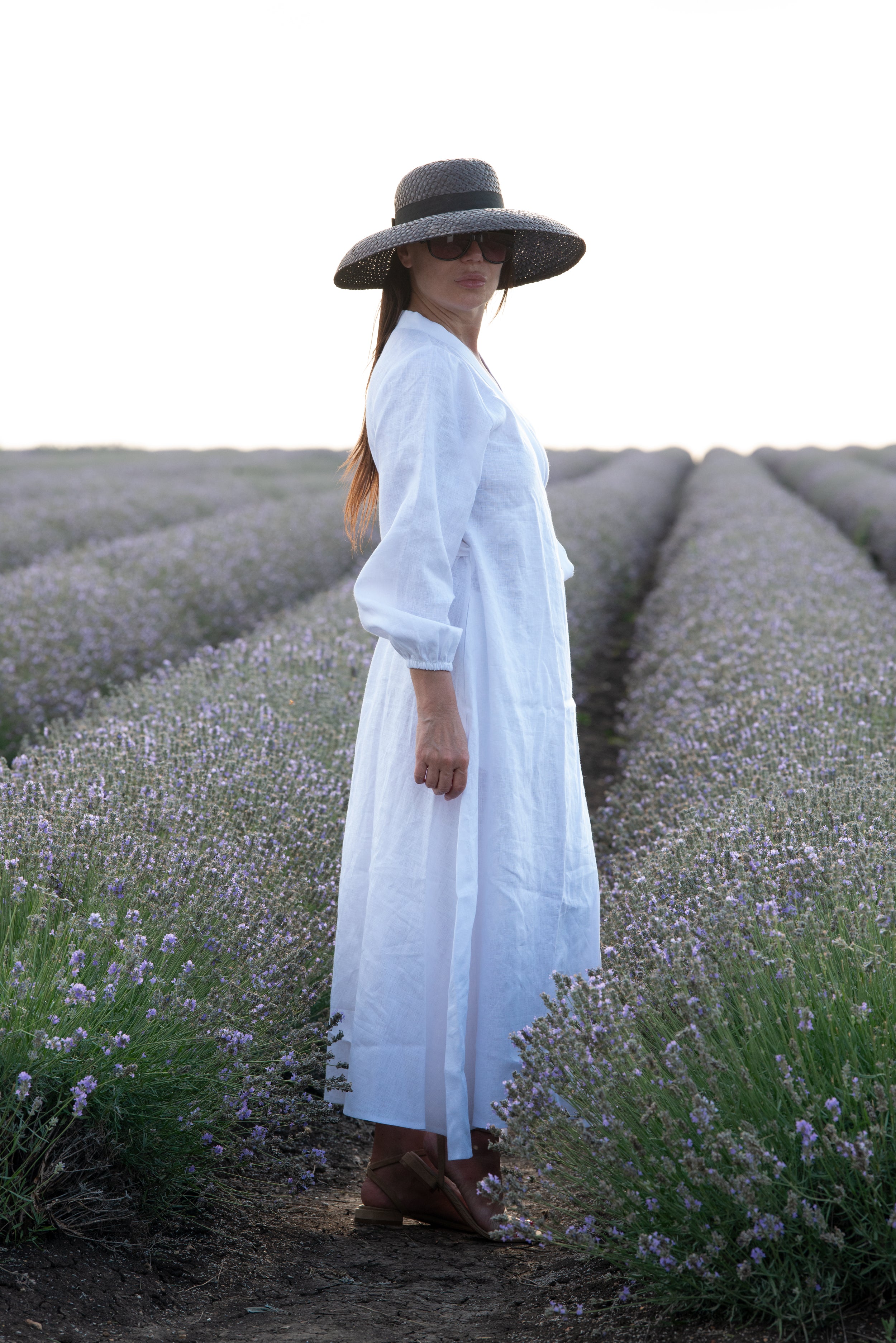 Woman in a white dress and wide-brimmed hat standing in a lavender field.