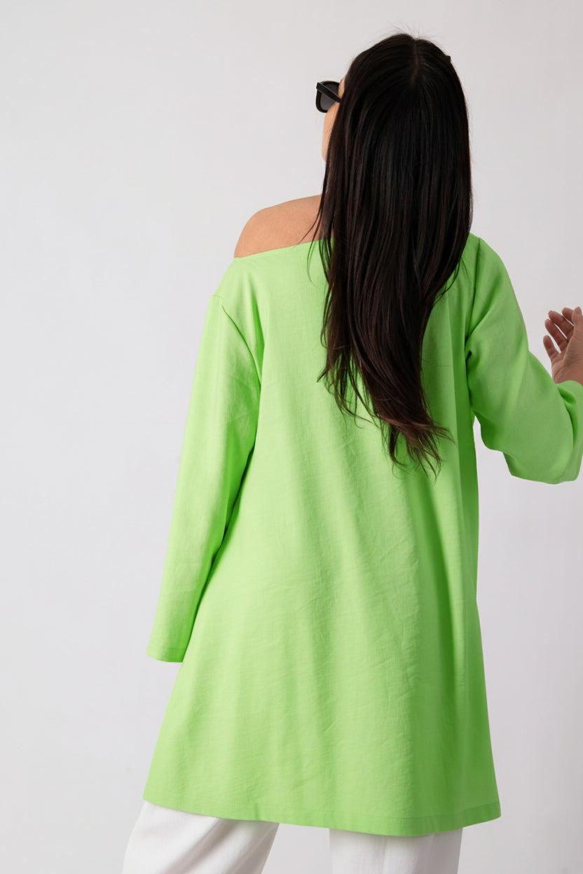 Person wearing a bright green off-shoulder top against a white background