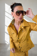 Woman wearing a mustard yellow outfit with sunglasses indoors
