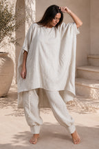Woman wearing a loose-fitting white outfit in an outdoor setting.