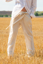 Person wearing light-colored pants and a white shirt standing in a wheat field.