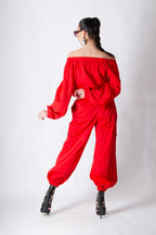 Person wearing a red off-shoulder jumpsuit on a white background