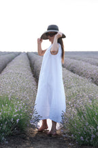 Woman in a white dress and black hat standing in a lavender field.