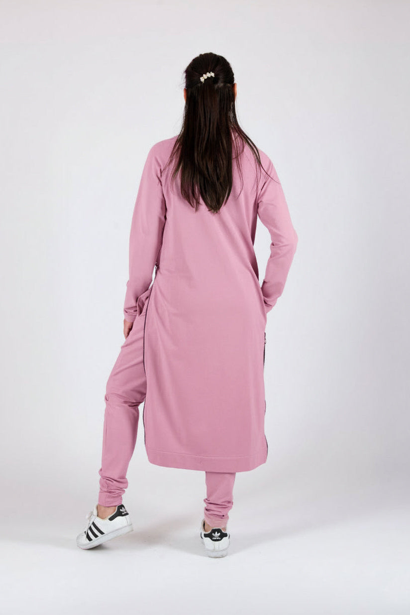 Person wearing a pink outfit with long sleeves and pants on a white background