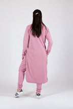 Person wearing a pink outfit with long sleeves and pants on a white background