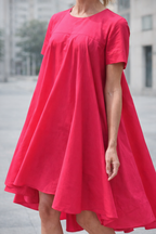 Person wearing a bright pink dress standing outdoors with a blurred background