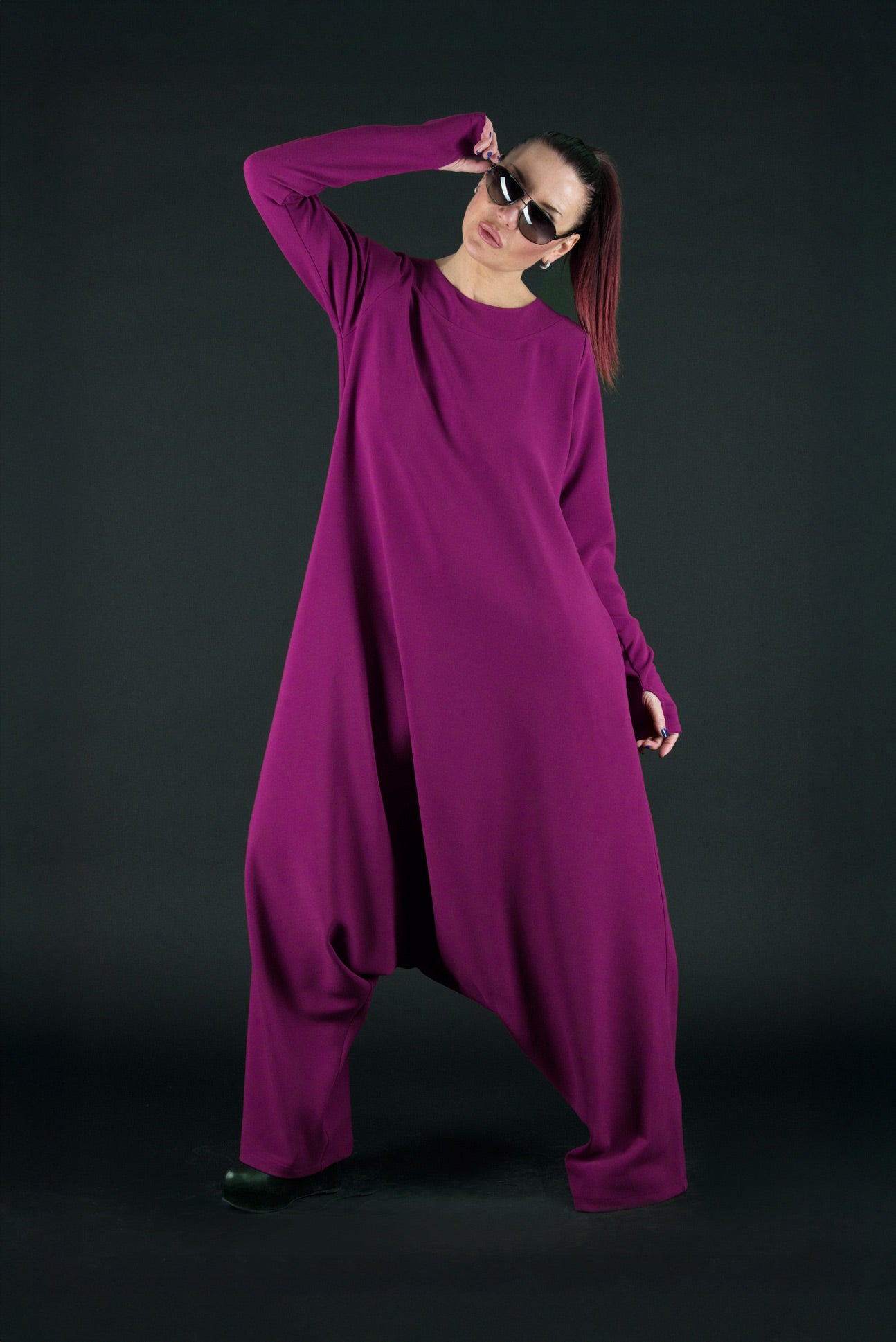 Person wearing a long purple dress against a black background