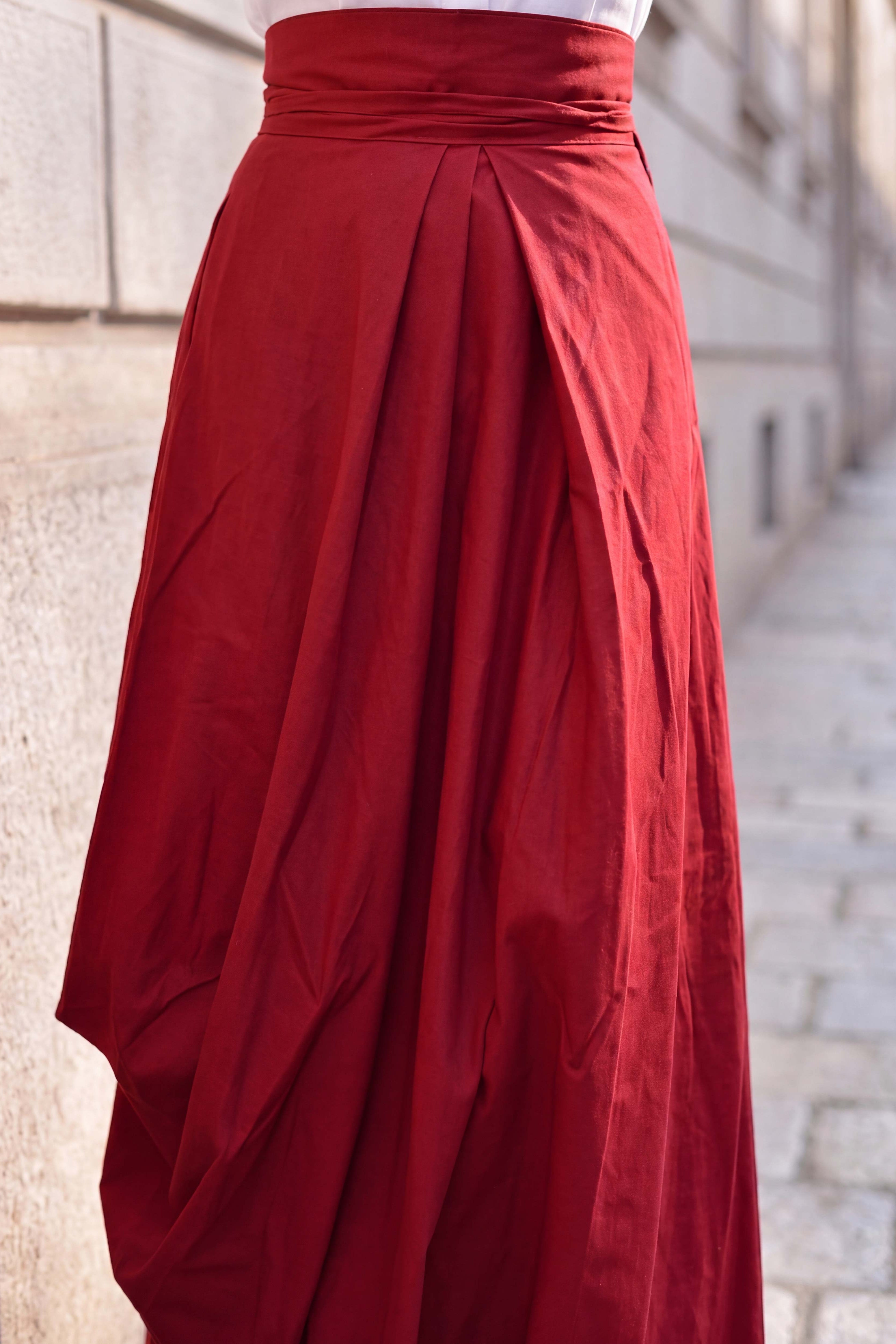 Red skirt with a draped design against a stone wall background