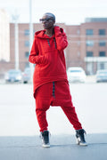Person wearing a red tracksuit standing on a street with buildings in the background