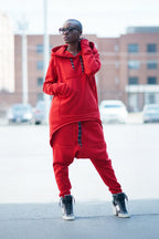 Person wearing a red tracksuit standing on a street with buildings in the background