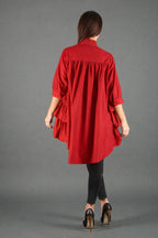 Person wearing a red dress over black pants on a gray background