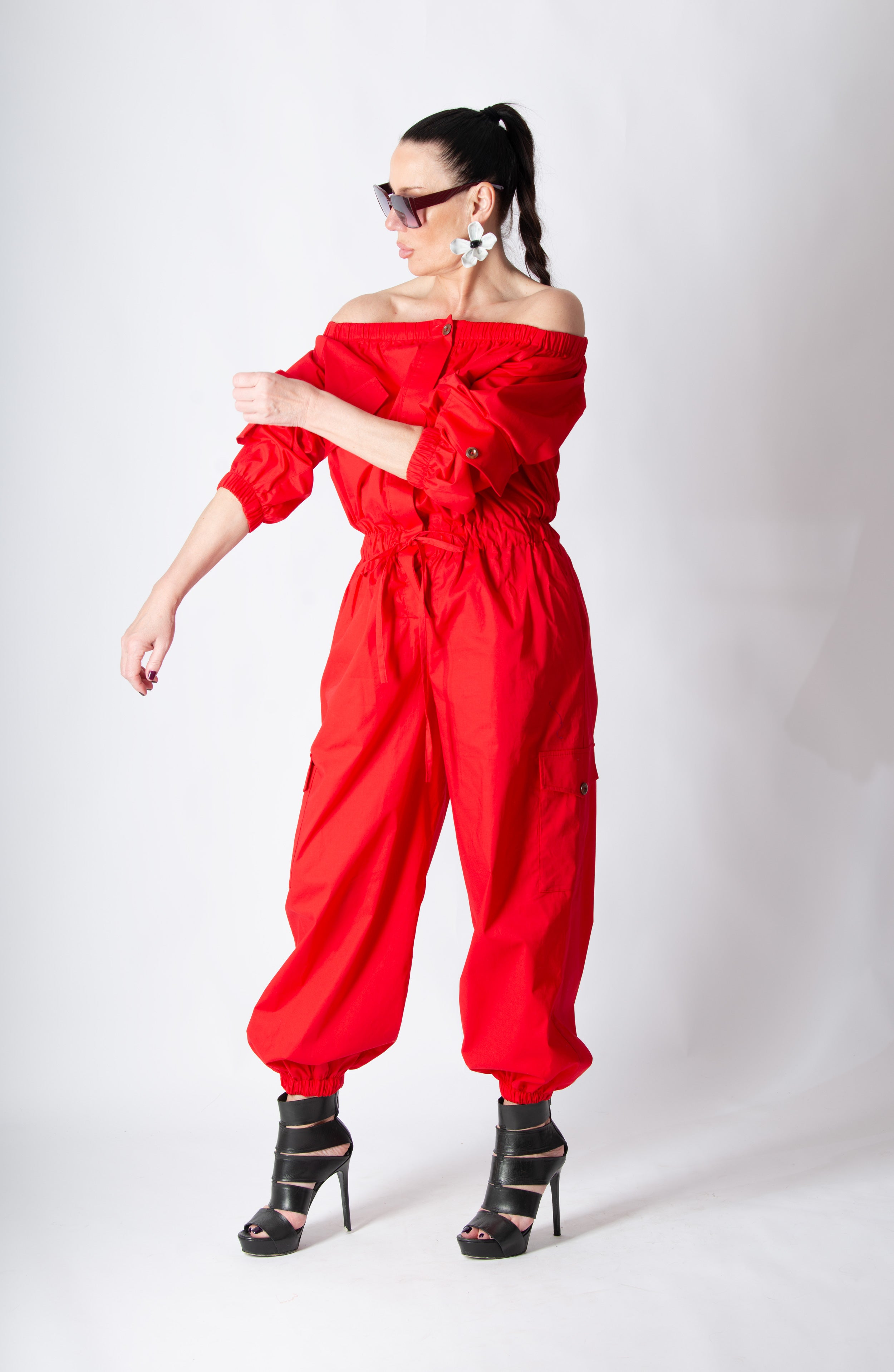 Woman wearing a red off-shoulder jumpsuit on a white background