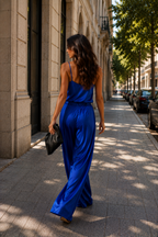 Woman in a blue jumpsuit walking down a city street.