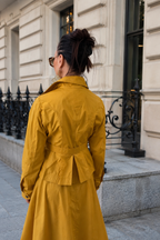 Person wearing a yellow trench coat standing on a city street.
