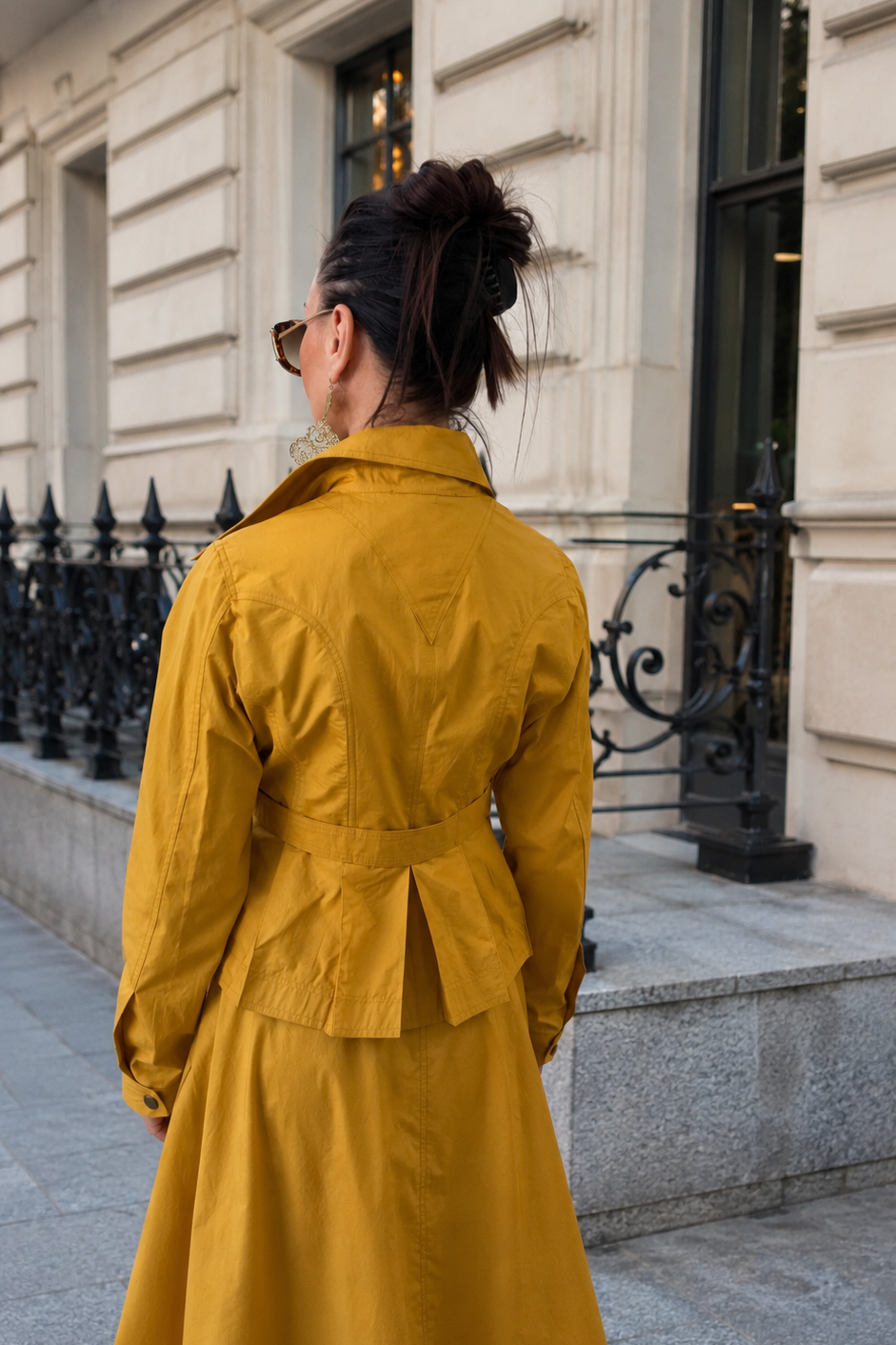Person wearing a yellow trench coat standing on a city street.