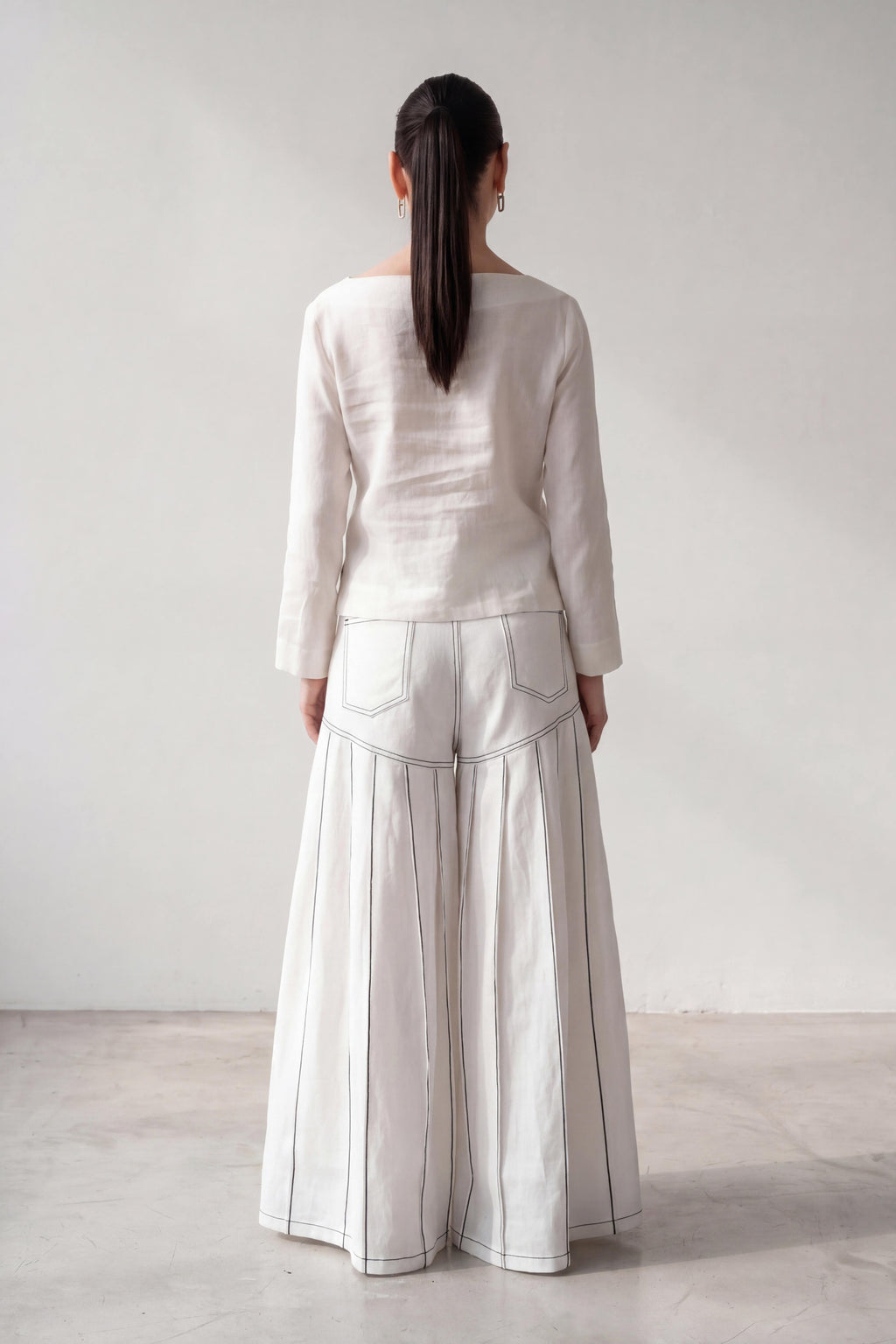 Person wearing a white outfit with wide-leg pants against a plain background