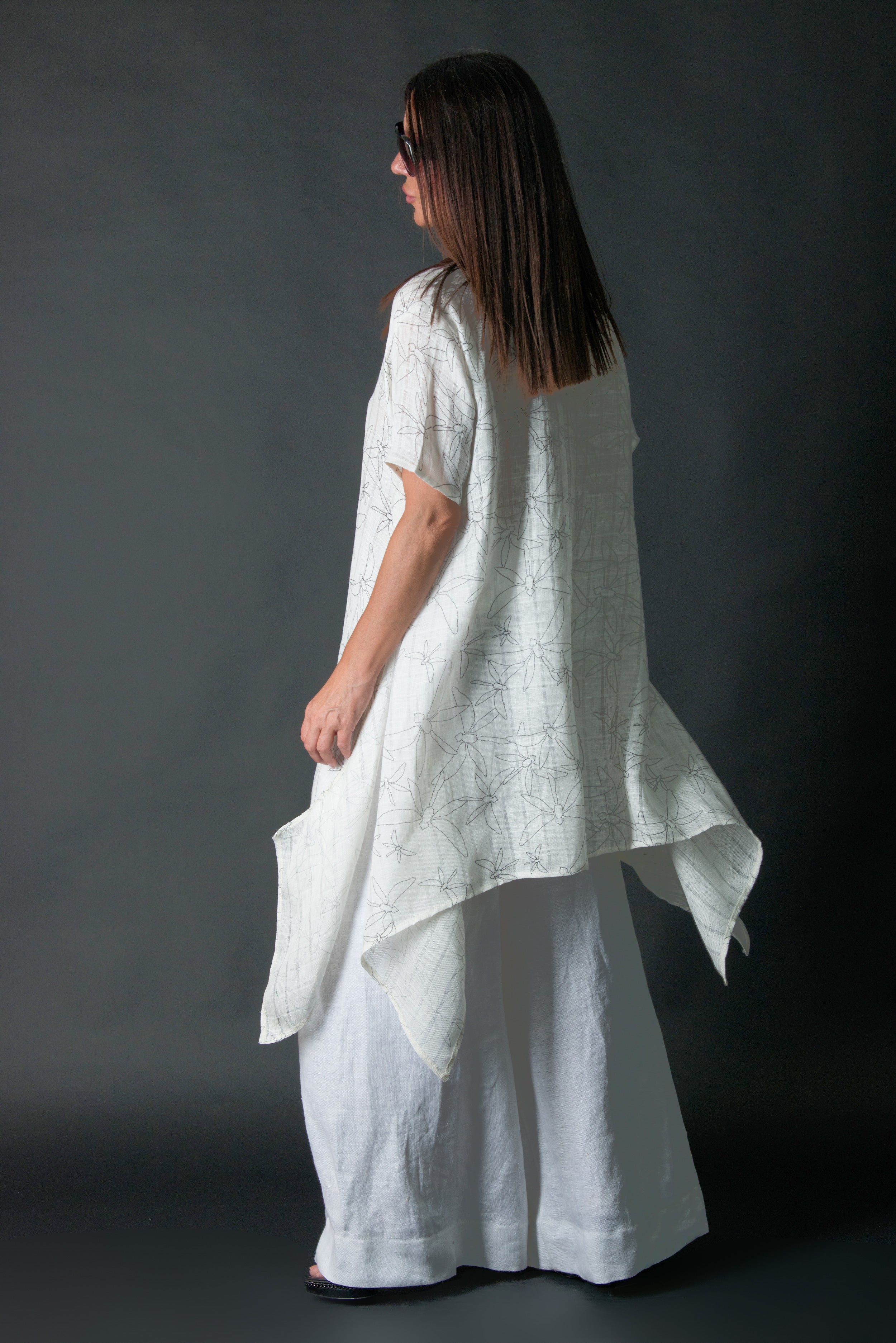 Woman wearing a white linen dress against a dark background