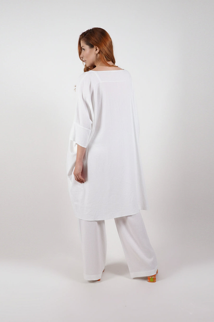 Woman wearing a white long-sleeve top and wide-leg pants on a white background