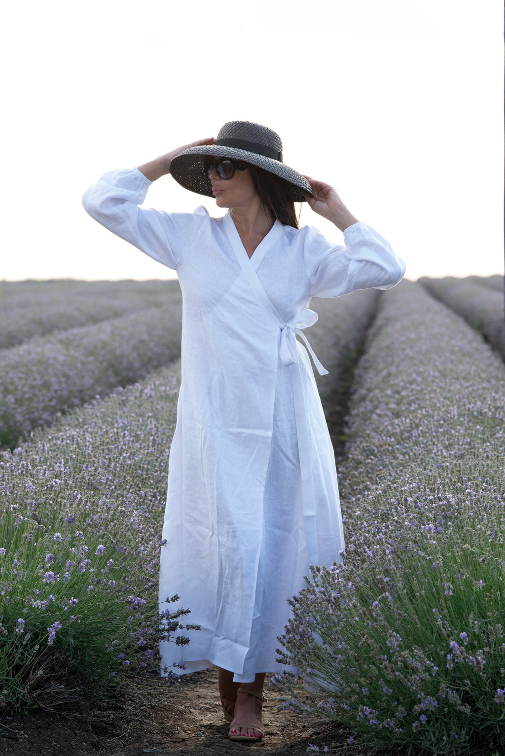 Woman in a white dress and black hat standing in a lavender field