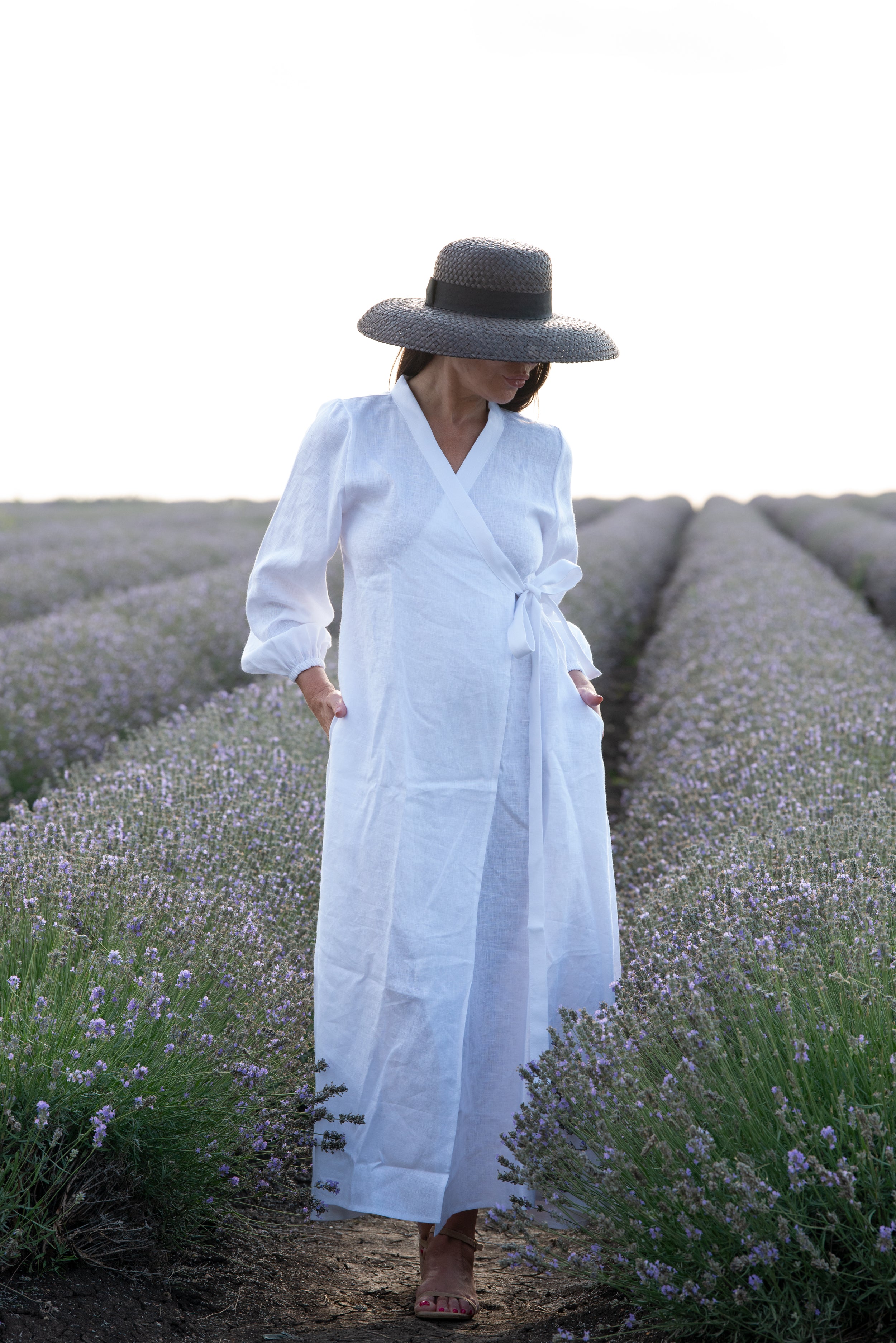 Woman in a white dress and black hat standing in a lavender field