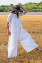 Woman in a white dress and wide-brimmed hat standing in a wheat field.