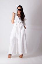 Woman wearing a white jumpsuit with ruffled sleeves against a plain background