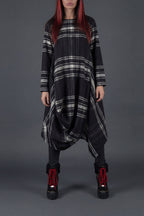 Person wearing a black and gray plaid dress with red hair against a gray background