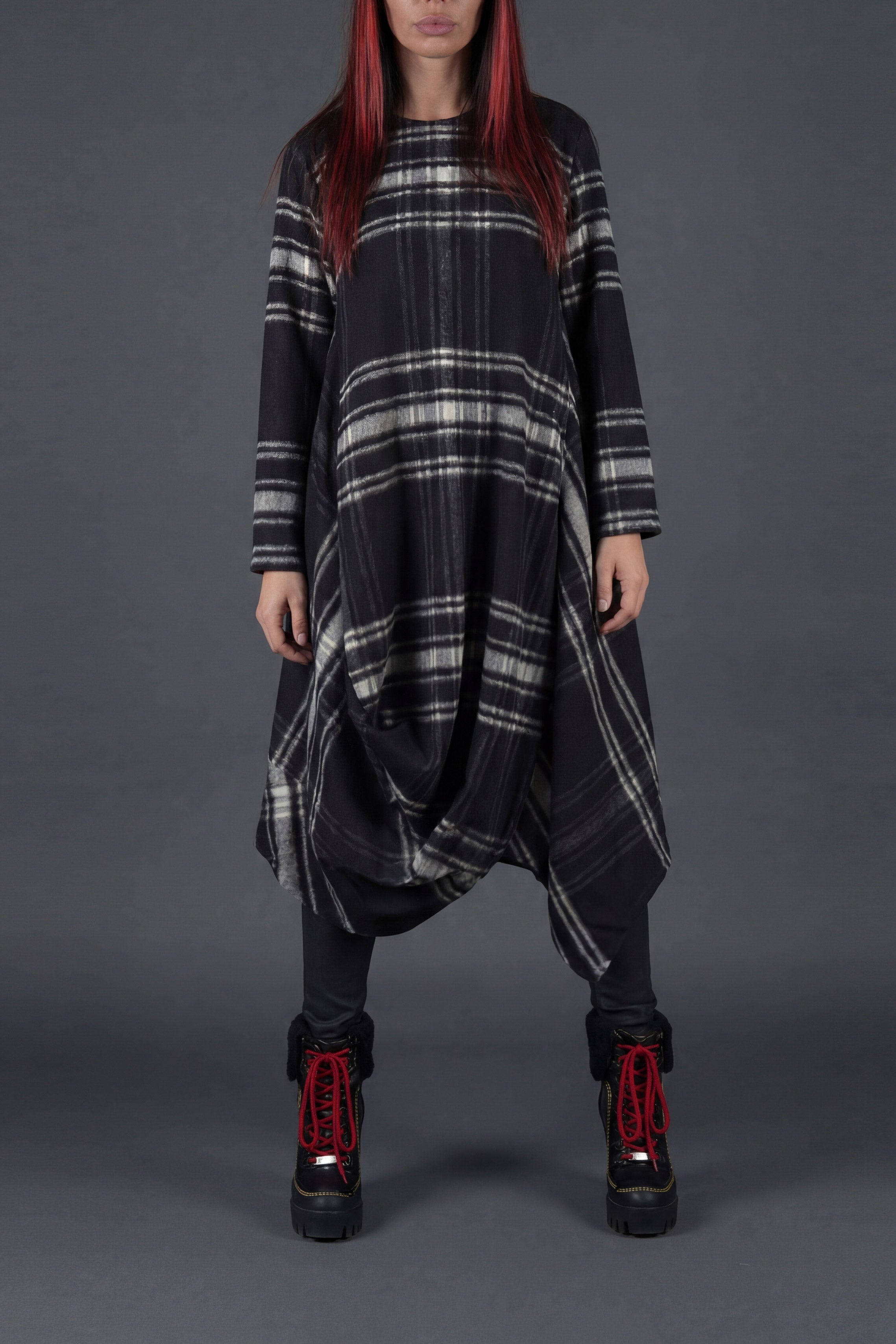 Person wearing a black and gray plaid dress with red hair against a gray background