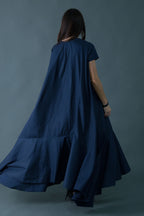 Woman wearing a long blue dress against a gray background