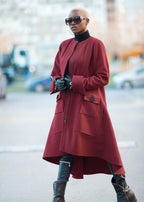 Person wearing a red coat and black boots on a street.
