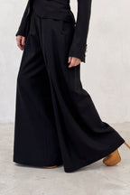 Person wearing a black outfit with a long skirt on a white background