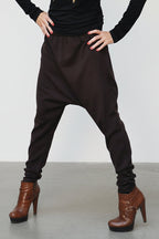 Person wearing black high-waisted pants and brown boots on a plain background