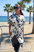 Woman walking on a wooden boardwalk by the beach with palm trees and ocean in the background.