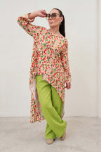 Woman wearing a floral top and green pants against a white background