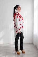 Woman wearing a white coat with red floral patterns in a minimalistic setting