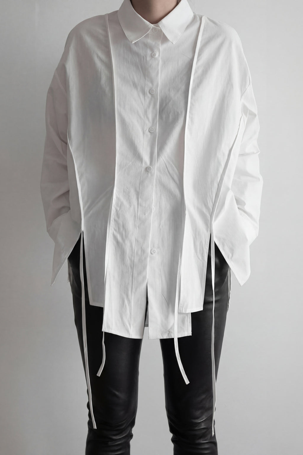 White shirt with long sleeves and black pants on a plain background