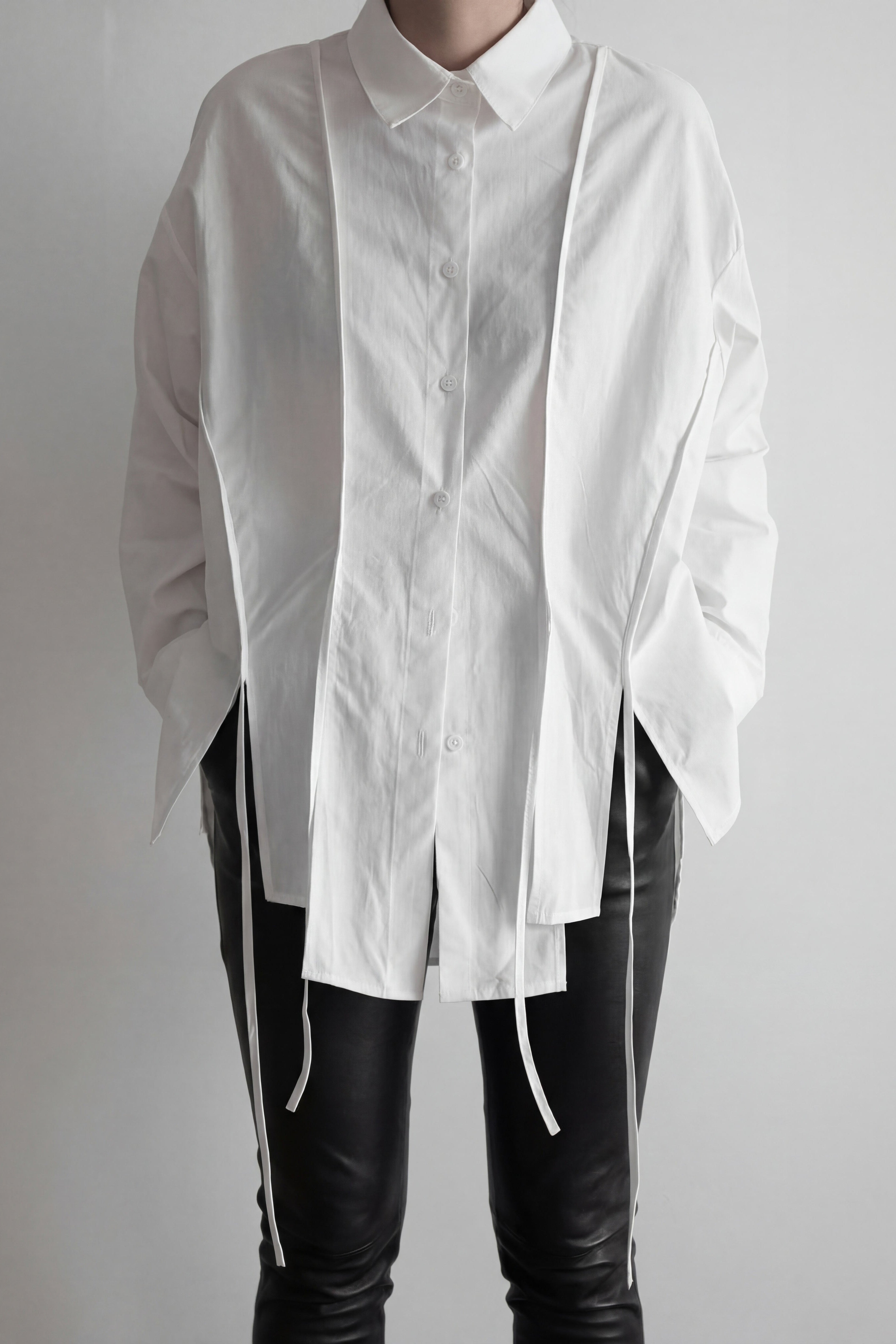White shirt with long sleeves and black pants on a plain background