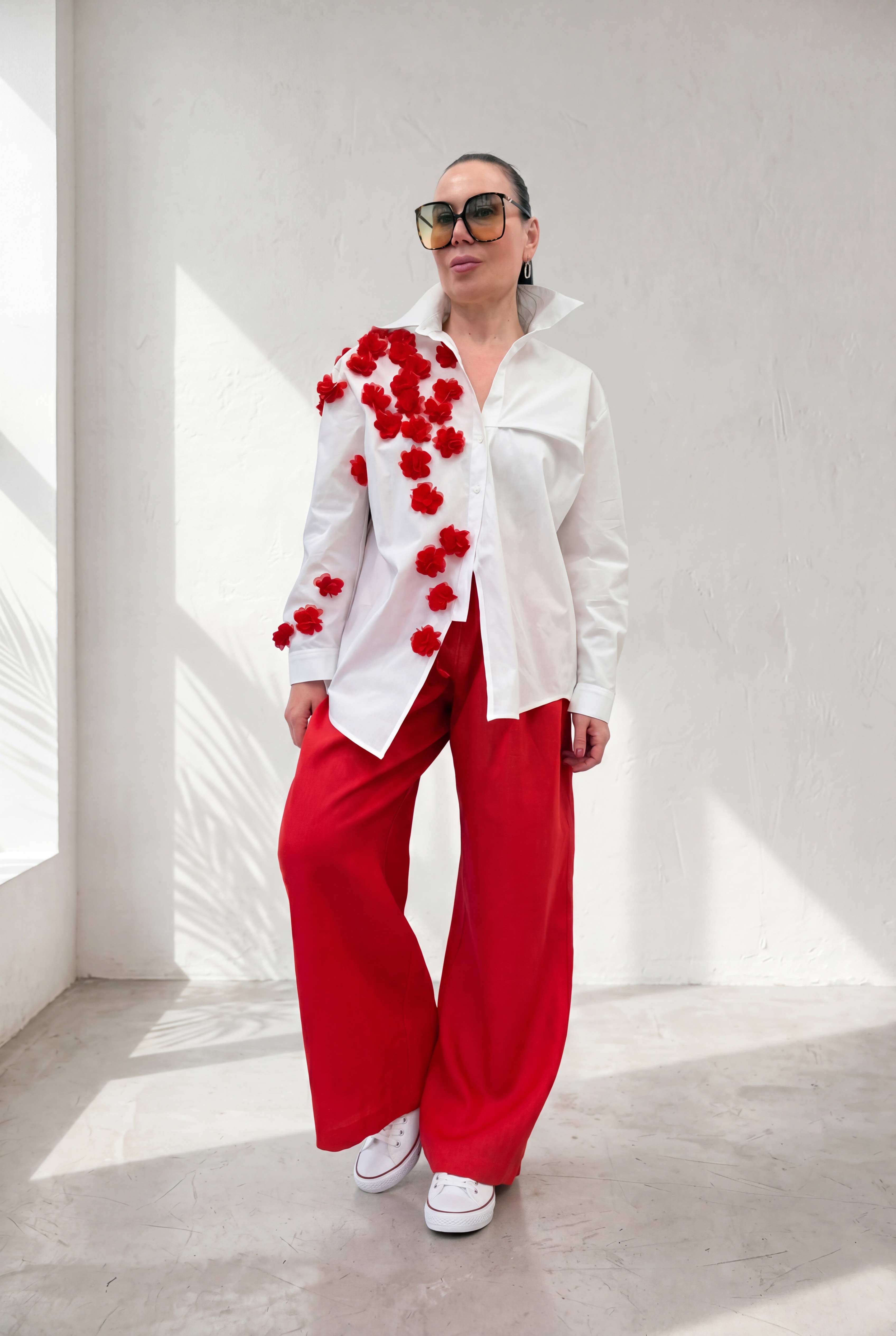 Person wearing a white outfit with red floral details against a white background