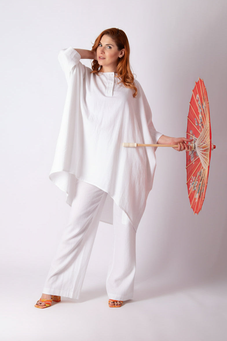 Woman in a white outfit holding a red umbrella against a white background