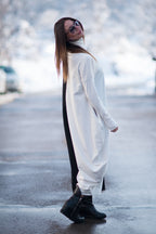 Woman in a long white coat standing on a snowy street