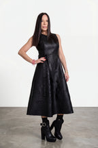 Woman wearing a black dress with a textured pattern on a white background