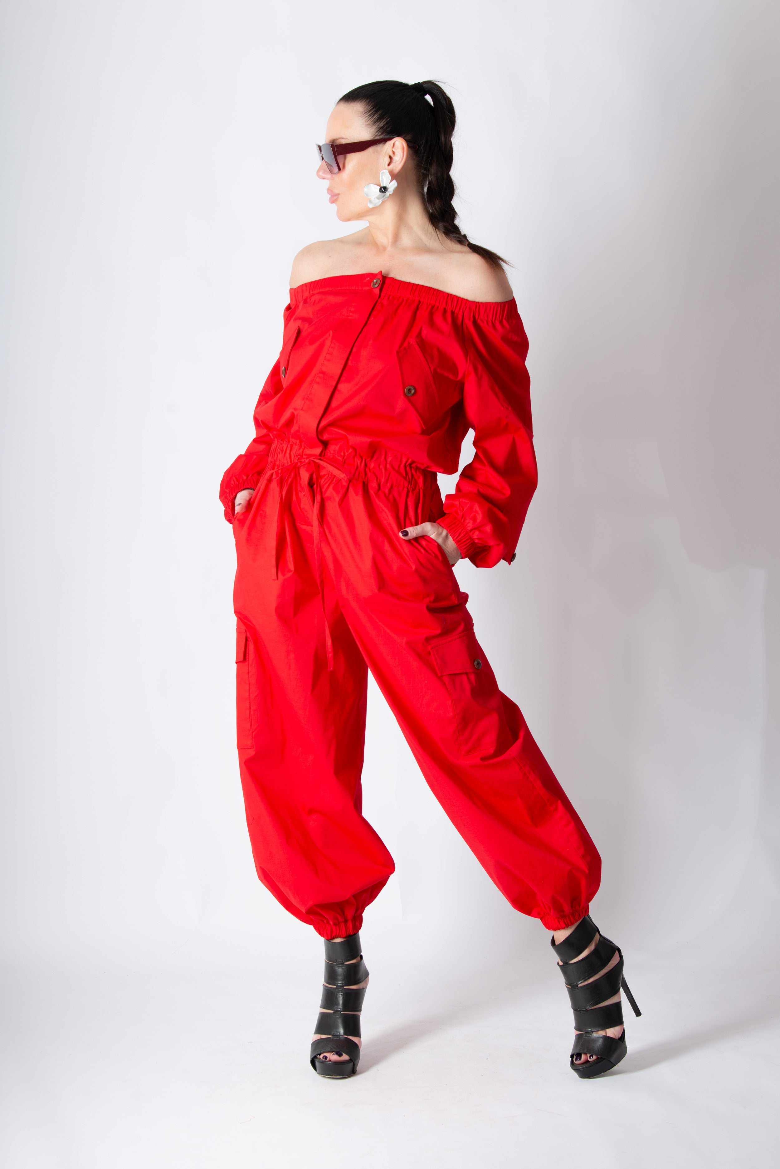 Woman wearing a red outfit with off-shoulder top and high-waisted pants on a white background